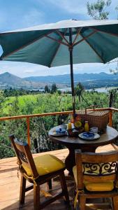 a table and chairs on a deck with an umbrella at Glamping blue. in Guatavita