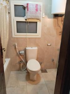 a small bathroom with a toilet and a window at شقة راقية مطلة علي كورنيش النيل المعادي - عوائل فقط in Cairo