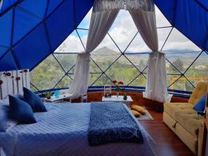 um quarto com uma cama azul e uma grande janela em Glamping blue. em Guatavita