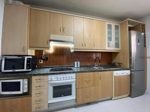 a kitchen with wooden cabinets and stainless steel appliances at Casa La Dulce Olaya a pocos minutos de Oviedo 