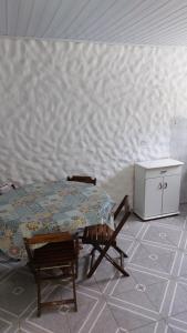 a table and chairs in a room with a wall at Maury Chalés Boiçucanga in São Sebastião