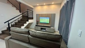 een woonkamer met een bank en een televisie bij Casa Alissa in Bonito