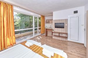 a bedroom with a large window and a television at Relax Larrisa Studio in Primorsko