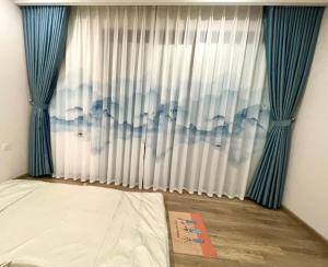 Schlafzimmer mit einem Bett und einem Fenster mit blauen Vorhängen in der Unterkunft Anna House Homestay in Kim Quan