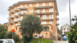 wysoki pomarańczowy budynek z samochodami zaparkowanymi przed nim w obiekcie Giuly House w Arenzano