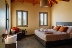 a bedroom with a bed and a couch and windows at Gea Mani Villas in Agios Nikolaos