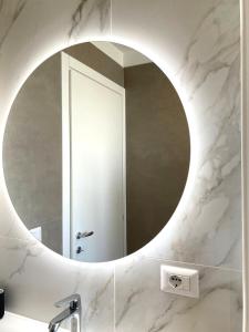 a bathroom with a round mirror on a marble wall at Bilocale moderno - Lorenteggio 145 in Milan
