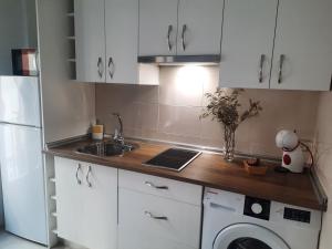 a kitchen with white cabinets and a sink and a washer at Apartamentos Clavero 10 in Plasencia