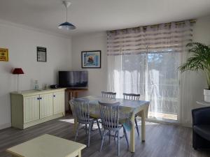 een woonkamer met een tafel en stoelen en een televisie bij Résidence Rose des Vents in Jullouville-les-Pins