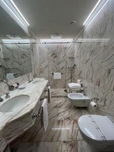 a marble bathroom with two sinks and a toilet at Hotel Al Duca Di Venezia in Venice