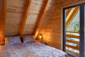 a bed in a wooden room with a window at Vila Marija HP in Han Pijesak