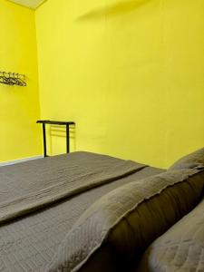 Kampong Wakaf TengahにあるTeratak Tok Ma Rumah Nyatuhの黄色い壁のドミトリールームのベッド1台分です。