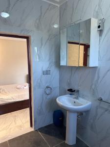 a bathroom with a sink and a mirror and a bed at Apartments Plaza Hotel in Kololi