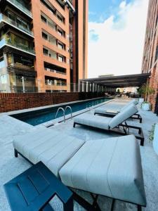 a swimming pool with two chaises and a sidx sidx sidx at Avellino 3BR Zona 10 Luxury Suite - Pool, Gym & View in Guatemala