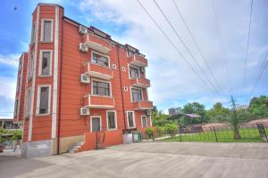 a red building with white windows on a street at Family Apartments in Batumi in Batumi