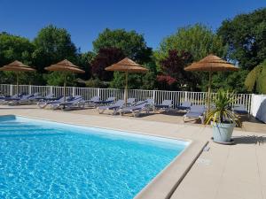 una piscina con sillas y sombrillas en Chant des Oiseaux ***, en Royan