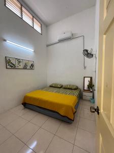 1 dormitorio con 1 cama con manta amarilla en Solehah Homestay, en Seri Iskandar