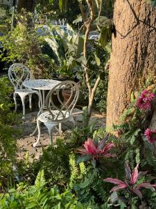 uma mesa e cadeiras num jardim com flores em Sandra’s sweet house em Chiang Mai