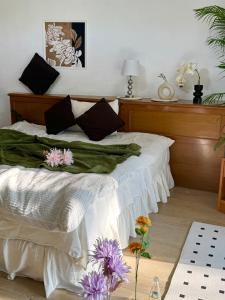 um quarto com uma cama com lençóis brancos e flores roxas em Sandra’s sweet house em Chiang Mai