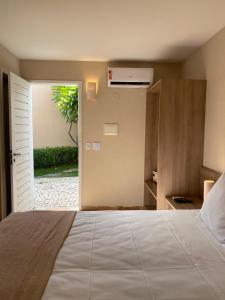 een slaapkamer met een bed en een deur met een plant bij Pousada Tropical Ilhas in Aquiraz