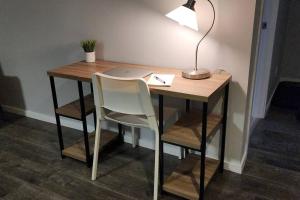 einen Schreibtisch mit einer Lampe und einem Stuhl mit einem Laptop in der Unterkunft Guest Suite in Saint Hubert, bus to REM and Metro in Longueuil