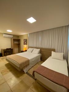 Habitación de hotel con 2 camas y mesa en Pousada Tropical Ilhas en Aquiraz