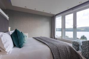 a bedroom with a large bed with a large window at Fern View House over Loch Ness in Inverness