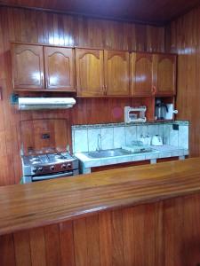 a kitchen with wooden cabinets and a stove and sink at DouchkaHouse in Puerto Maldonado