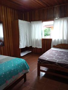 a bedroom with a bed and a window with white curtains at DouchkaHouse in Puerto Maldonado