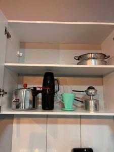 ein Küchenregal mit Kaffeemaschine, Töpfen und Pfannen in der Unterkunft Confortável APTO em Boa Vista. in Boa Vista