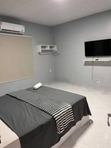 a room with a bed and a flat screen tv at Confortável APTO em Boa Vista. in Boa Vista
