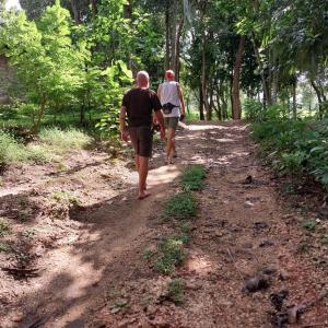 two people walking down a dirt road with trees at Ridge Boundary View in Dambulla