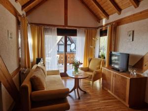 ein Wohnzimmer mit einem Sofa, einem TV und einem Tisch in der Unterkunft Haus Bachmatt in Sasbachwalden