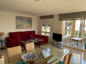 a living room with a red couch and a tv at Charming 3 Bedroom apartment with sea view in the heart of Sotogrande in Sotogrande
