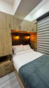 Cette chambre comprend un grand lit et des placards en bois. dans l'établissement Living para 2 personas, Apartaestudio - Santa Bárbara, Bogotá, à Bogotá