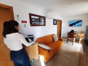 a woman standing in a living room playing a video game at Burguesinha AL Entre-os-Rios in Entre-os-Rios