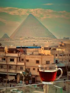 a cup of tea sitting on a ledge with the pyramid at pyramids stone Top in Cairo
