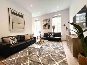 ein Wohnzimmer mit einem schwarzen Sofa und einem Tisch in der Unterkunft 1 Bed Apartment moments from Kings Cross Station! in London