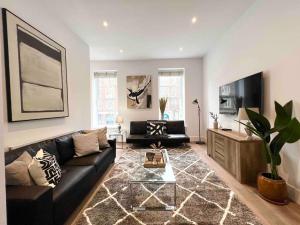 ein Wohnzimmer mit einem schwarzen Sofa und einem TV in der Unterkunft 1 Bed Apartment moments from Kings Cross Station! in London