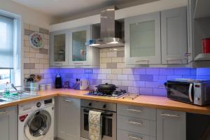 uma cozinha com armários brancos e azulejos azuis em Sunny Queens Park Home - Garden & Private Parking em Brighton & Hove