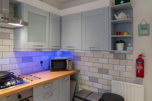 uma cozinha com armários brancos e azulejos azuis em Sunny Queens Park Home - Garden & Private Parking em Brighton & Hove