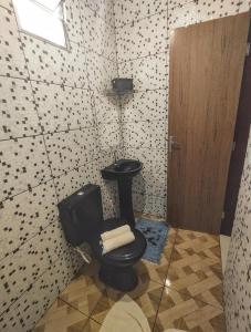 baño con aseo negro y lavamanos en Casinha do Beco 01, en Lençóis