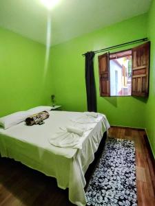 1 dormitorio verde con 1 cama con ventana en Casinha do Beco 01, en Lençóis