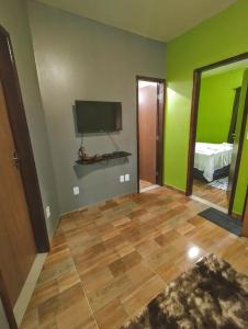sala de estar con paredes verdes y TV en Casinha do Beco 01, en Lençóis
