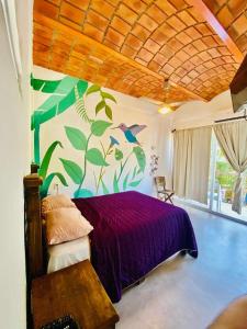 a bedroom with a purple bed with a painting on the wall at Habitacion privada con pisicina y cocina compartida in Sayulita