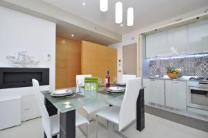 uma cozinha com uma mesa de vidro e cadeiras brancas em Suite Gallipoli con vista mare da 4 posti e wifi em Gallipoli