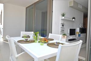 uma sala de jantar branca com uma mesa e cadeiras brancas em Suite Gallipoli con vista mare da 4 posti e wifi em Gallipoli