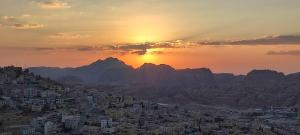 uma cidade com o pôr do sol atrás das montanhas em Rocky Mountains Hotel em Wadi Musa