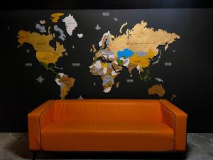 an orange couch with a map of the world on a wall at Atlas Hotel in Almaty
