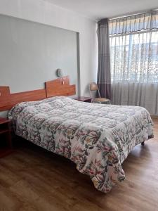 a bedroom with a bed with a floral bedspread and a window at América inn in Puno